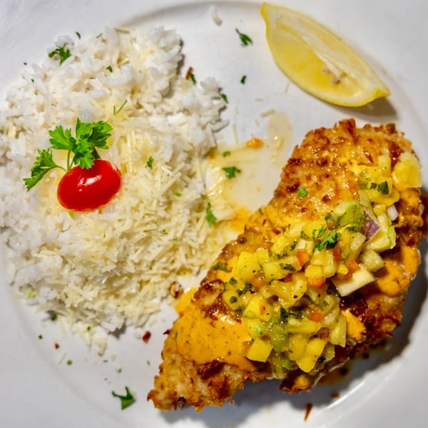 Crispy fish with mango salsa, rice, and a lemon wedge on a white plate at The Fish House.
