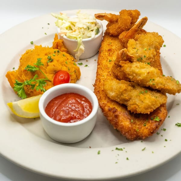 Fried fish and shrimp with mashed sweet potatoes, coleslaw, ketchup, and a lemon wedge.