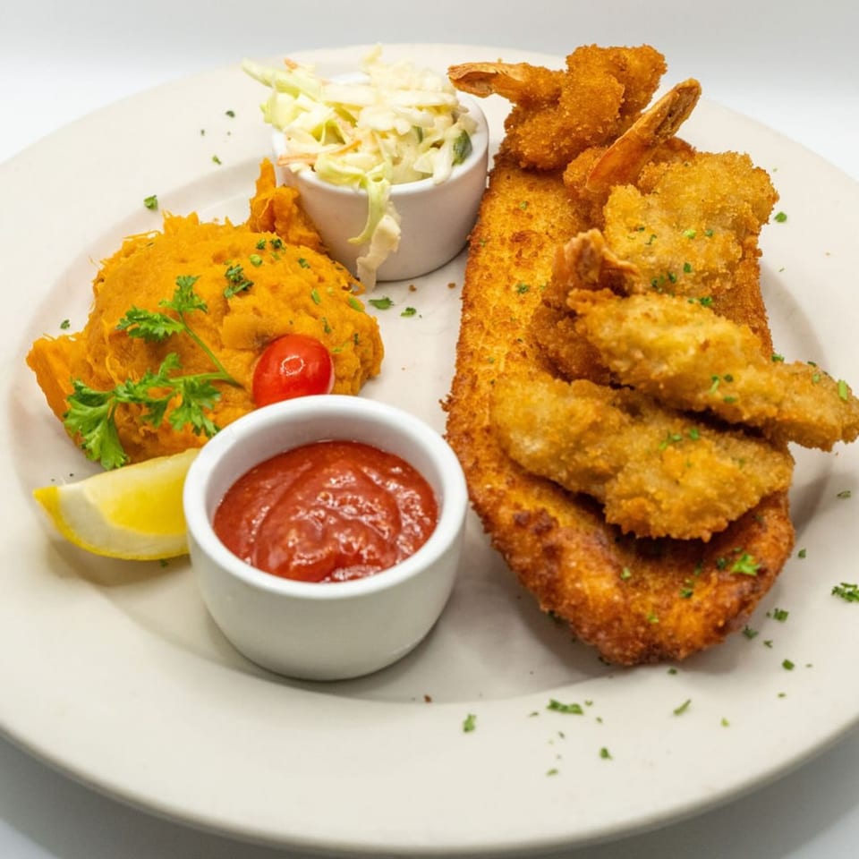 Fried fish and shrimp with mashed sweet potatoes, coleslaw, ketchup, and a lemon wedge.