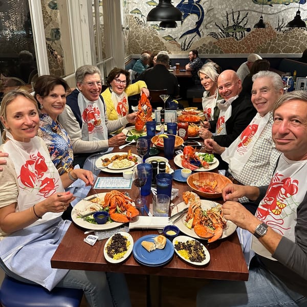 A group of happy diners wearing lobster bibs, enjoying whole lobsters and seafood at The Fish House.